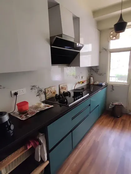 This parallel kitchen features a striking combination of ocean blue laminate cabinets and a dark granite countertop. The wooden flooring adds warmth to the modern design. This layout maximizes counter space and storage in a narrow area.
