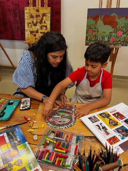 An instructor helps a young boy with his Basquiat-inspired piece, demonstrating how to use oil pastels to create bold, energetic marks.