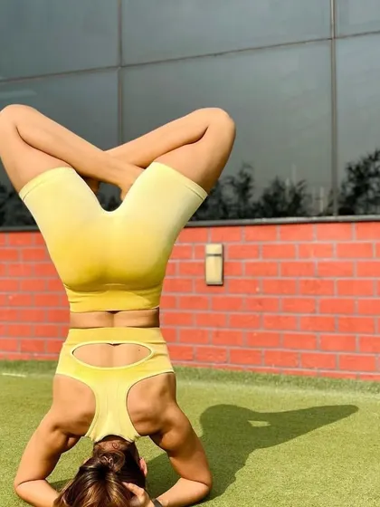 Mastering the art of balance and strength with grace. This client holds a Sirsasana Pada Padmasana (Headstand with Lotus Legs), a beautiful and challenging yoga pose, on our outdoor turf.