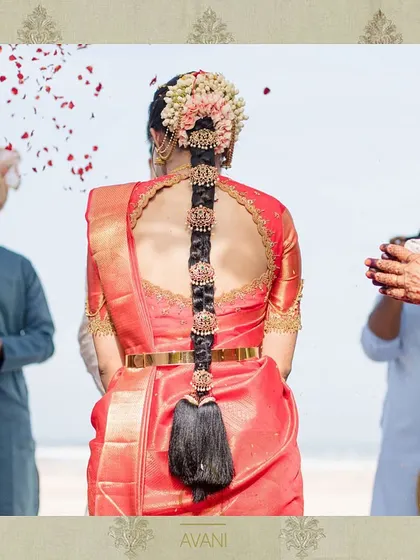 A bride on her wedding day, showcasing the back of her red blouse with a circular cutout and detailed embroidery. The design is both traditional and stylish, perfect for a modern bride.