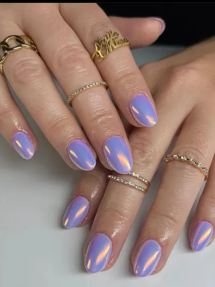 A full view of the stunning iridescent lavender chrome nails, accessorized with gold rings.