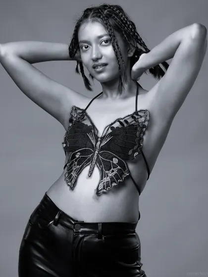 A black and white shot of the model, with a playful and confident expression.