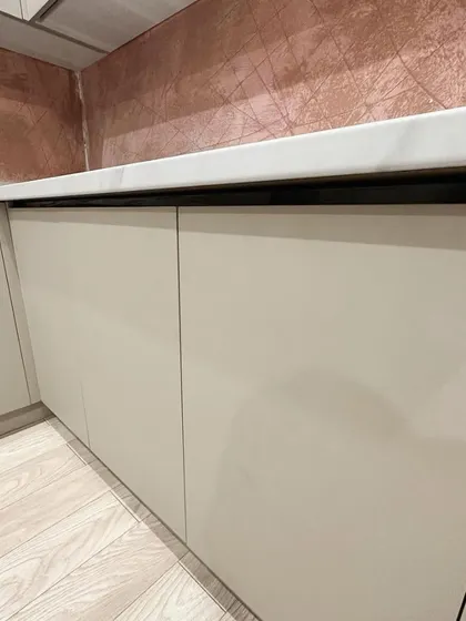 A close-up of the handle-less base cabinets, showing the clean lines and flawless matte finish. The design uses a Gola profile system for easy opening without external hardware.