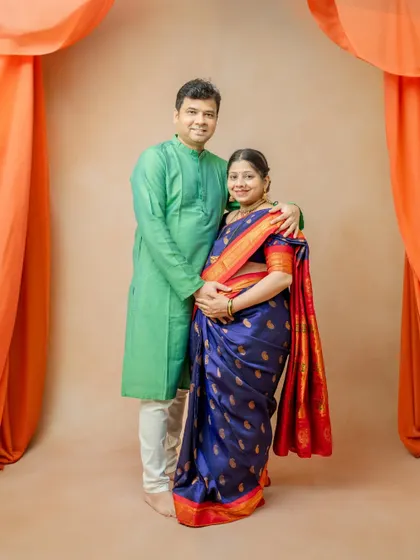A lovely couple's portrait in traditional Indian wear. The husband's green kurta complements the wife's deep blue and red saree, creating a colorful and harmonious image.