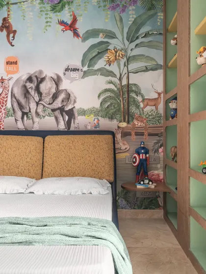 A close-up of the jungle mural and custom shelving unit. Every detail, from the colorful animals to the built-in nightstand, was designed to spark imagination and create a cozy, personalized space.