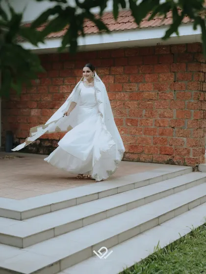 A joyful, dynamic shot of a Muslim bride in her flowing white dress, captured mid-twirl on an outdoor patio.