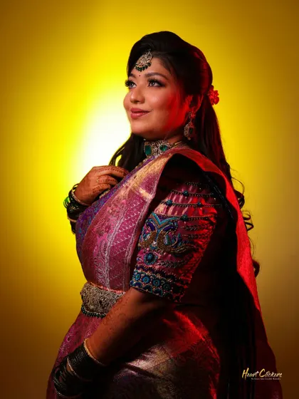 A classic bridal portrait with dramatic lighting that highlights the rich colors of her saree and her elegant pose.