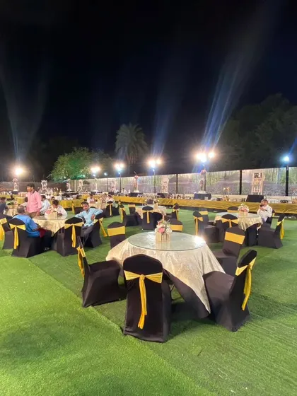 An outdoor event space with elegantly set round tables and a sprawling buffet line in the background. We manage everything to ensure a comfortable and grand dining experience for your guests.
