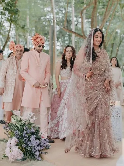 The bride's graceful entrance through a path lined with trees and candles. This shot captures the anticipation and elegance of the bridal procession.
