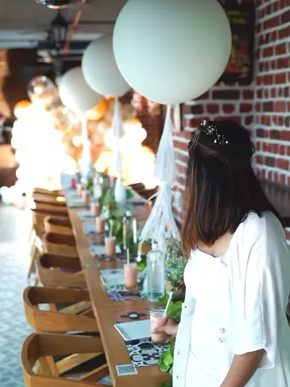 A throwback to a beautiful and intimate birthday celebration. The decor featured large white balloons and a rustic brick wall, creating a chic and modern party setting.