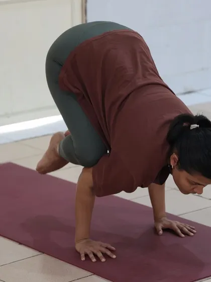 A student holds the crow pose with deep concentration. Arm balances like this improve focus and build confidence.