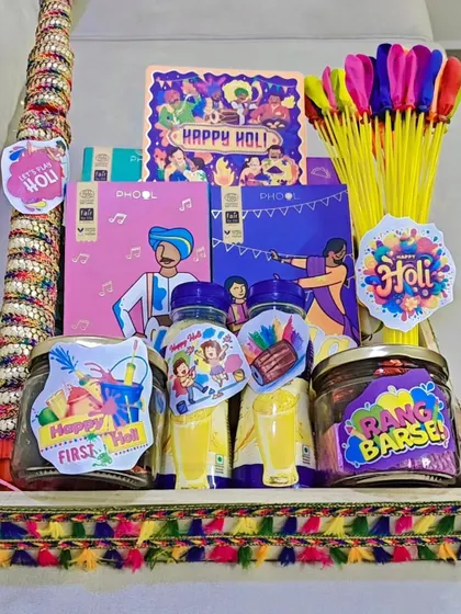 Holi is the festival of colors, and the gifts should be just as vibrant. This festive hamper is packed with everything needed for a fun celebration, including herbal gulaal from Phool, thandai bottles, water balloon pumps, and other playful goodies, all arranged in a decorated tray.