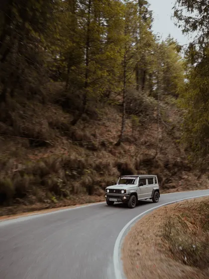 Photos of Suzuki Jimny and Ford Endeavour vehicles driving through dense pine forests and on open roads. These images showcase the capability of these vehicles in tough terrains.