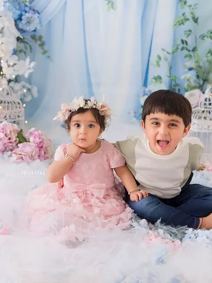 A duplicate of image 81, capturing a fun and silly moment between siblings in a floral wonderland setting.
