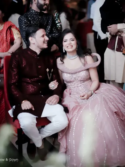 A happy, candid moment of the couple enjoying their engagement party from their seats. Their shared smile shows their excitement and joy.