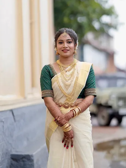 A full-length portrait of the Kerala bride. The makeup is designed to complement the simplicity and elegance of the kasavu saree.