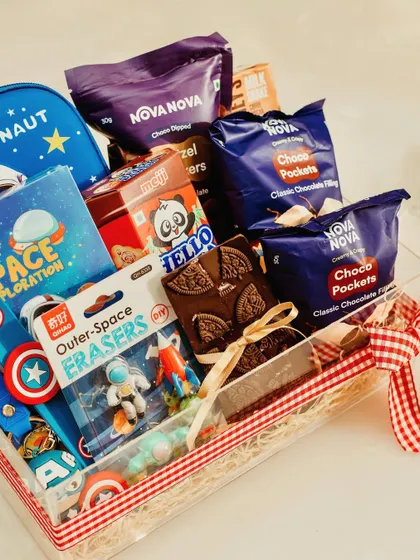 A closer look at the contents of our space-themed hamper, featuring an Avengers keychain, Hello Panda biscuits, and an Oreo chocolate bark, all packed in a clear acrylic tray.