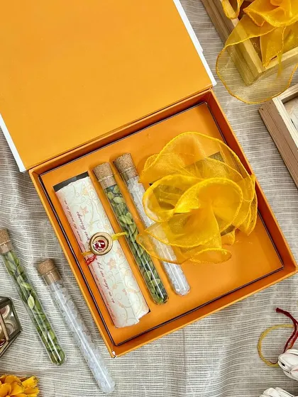 This wedding invitation box for Shambhavi and Joshua features a vibrant, hand-illustrated floral design. Inside, a custom scroll is nestled alongside glass tubes containing traditional spices, offering a multi-sensory experience for guests.
