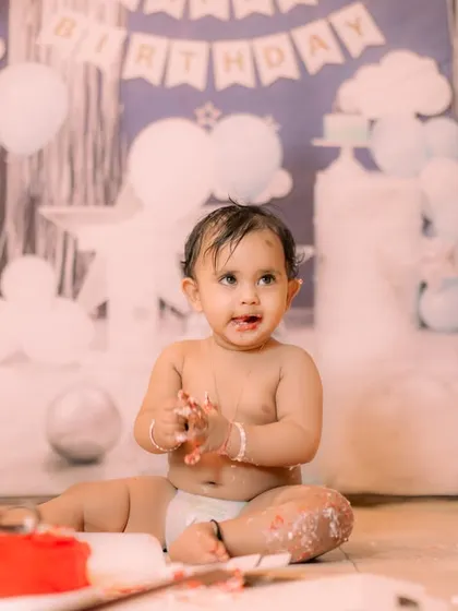 A classic boy's first birthday setup with a blue and white theme. The backdrop features clouds and a "Happy Birthday" banner, ideal for a simple and sweet cake smash session.