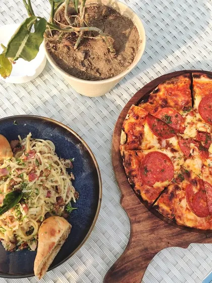 A classic pairing of pepperoni pizza and spaghetti carbonara, served al fresco. Our menu features a range of European and Indian classics to satisfy any craving.