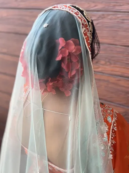 The same red floral bun, seen through a delicate veil, creating a soft and romantic effect.