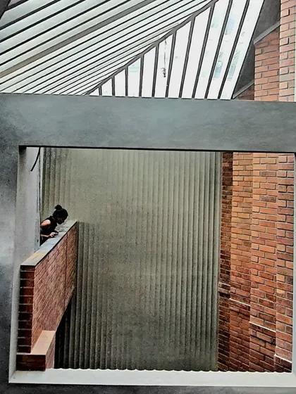 A framed view within the Brick House, where layers of brick, concrete, and a slatted skylight create a complex interplay of textures and light.