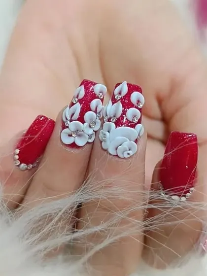 A close-up of our dramatic 3D floral design. The layers of sculpted white petals create incredible dimension against the sparkling red background, finished with rhinestone details.