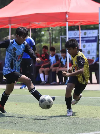 A thrilling semi-final match for our U-15 team. A player skillfully shields the ball from a defender, showcasing the strength and control needed in high-pressure games.
