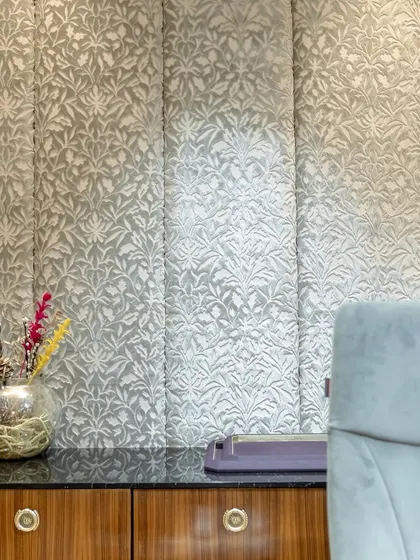 A detail shot of the fabric wall paneling behind the consultation desk. The intricate, raised pattern adds a tactile quality and a layer of visual interest to the space, enhancing its luxurious feel.