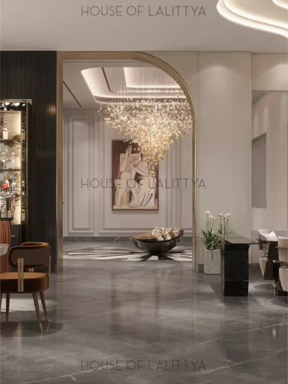We design spaces that flow effortlessly into one another. Here, a gracefully arched opening frames the view from the bar area into the main living space, where a stunning chandelier hangs as a focal point. The continuous marble flooring unifies the two zones.