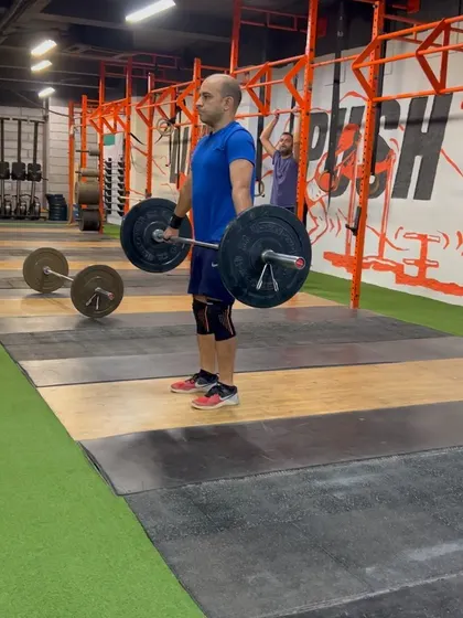 An athlete holding the bar at the "high hang" or "hip" position. Starting from here helps isolate and strengthen the final, most explosive part of the snatch pull.