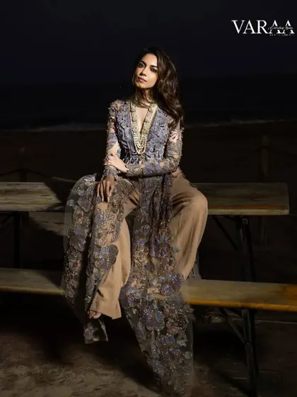 We styled this intricate, floor-length embroidered jacket over neutral trousers for a stunning beachside shot at dusk. This look for Varaa Magazine with Ritu Varma blends couture craftsmanship with a relaxed, natural setting.