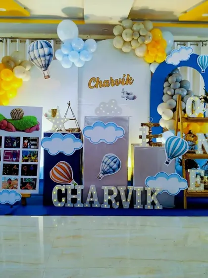 We created this beautiful hot air balloon theme for Charvik's first birthday. The setup includes a custom backdrop, a "My First Year" photo board, and a light-up number "1" for a personalized touch.