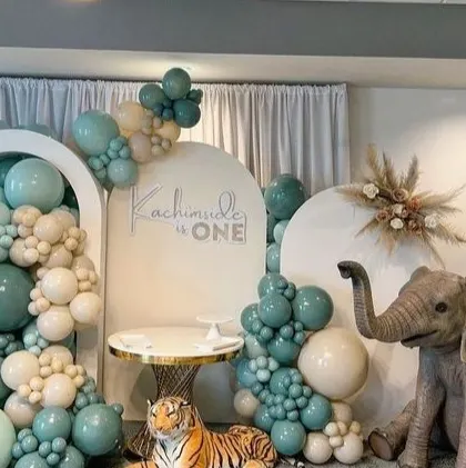 We bring wild adventures to life with our themed parties. This immersive jungle safari setup for a first birthday features lifelike animal props like a giraffe and elephant, set against custom arched backdrops and a lush balloon arrangement in sage green and neutral tones.