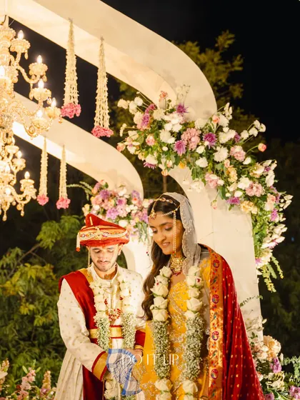 A candid moment from the pheras, framed by the grand floral arch and hanging chandeliers. The lighting was carefully designed to be warm and flattering, ensuring every moment was captured beautifully.