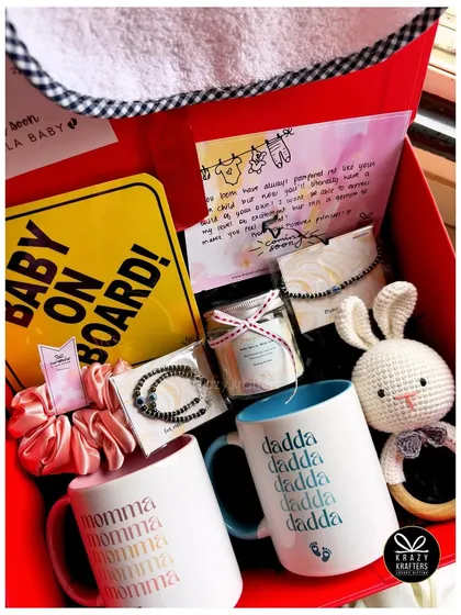A bright and cheerful hamper for parents-to-be, featuring 'Momma' and 'Dadda' mugs, a crochet rattle, a 'Baby on Board' sign, and an 'Aunt's Favourite' bib.
