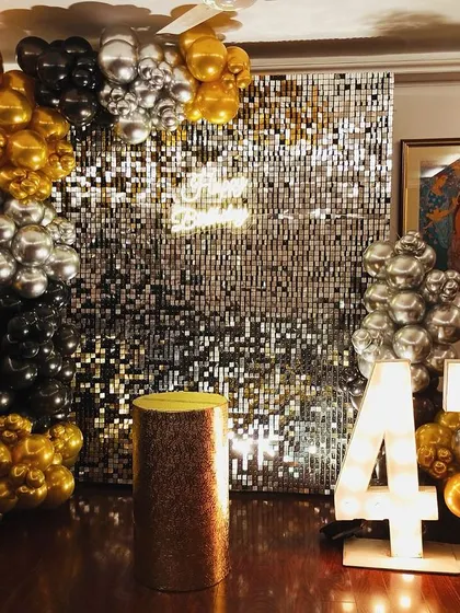 Celebrating 47 in style. This setup features a stunning silver sequin wall that catches the light beautifully, framed by a dramatic black, gold, and silver balloon arrangement. The marquee numbers add that perfect focal point for birthday photos.