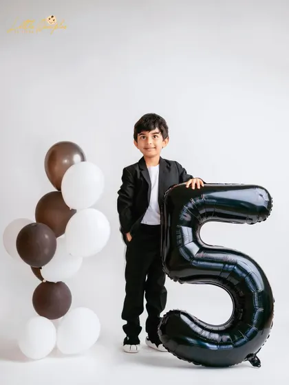 Posing with his age. Using balloon numbers is a fun way to mark the occasion in a milestone photoshoot.