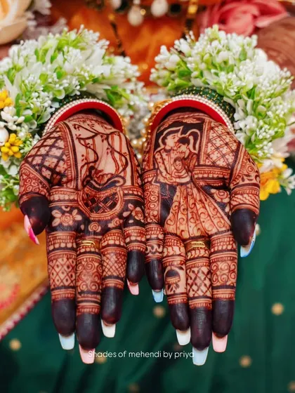 A beautiful shot of the bride's hands after the henna has stained. The dark, rich color highlights the intricate details of the wedding figures and patterns.