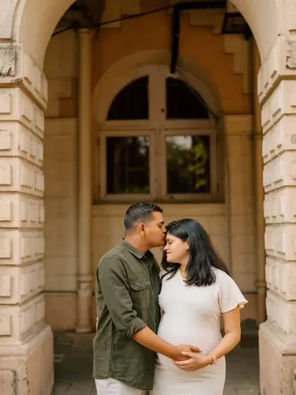 A tender moment shared between the couple against the backdrop of classic stone architecture, symbolizing the strong foundation of their growing family.