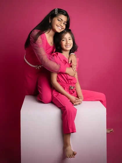 A sweet and gentle moment between two sisters. The older sister's embrace is so loving, creating a beautiful portrait of sisterhood.