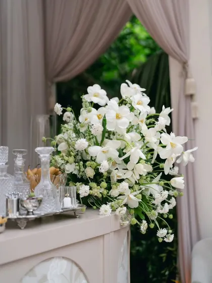 A simple yet stunning bouquet of white orchids and other delicate white flowers, placed on the bar. This shows how even small floral details can elevate the elegance of a space.