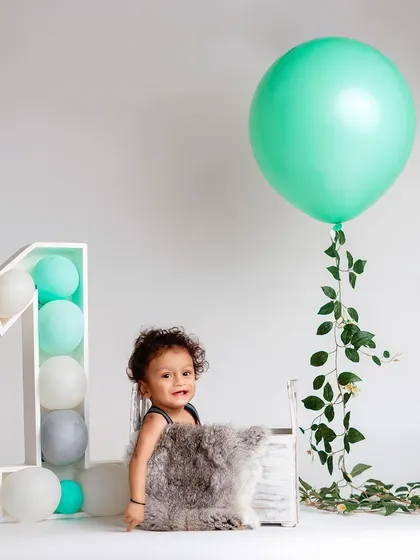 Simplicity can be so beautiful. This minimalist first birthday setup with a single balloon and clean background keeps the focus entirely on the child.