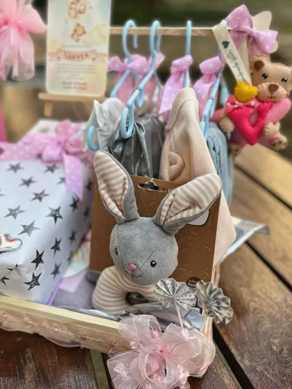 A close-up of the mini clothing rack, showing tiny outfits hung on individual hangers, each adorned with a delicate bow.