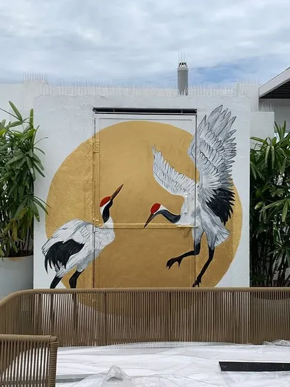 This mural on a textured rooftop wall in Bangalore was designed to cleverly conceal a door. The dancing cranes against a bold golden sun create a powerful focal point for this outdoor lounge area.