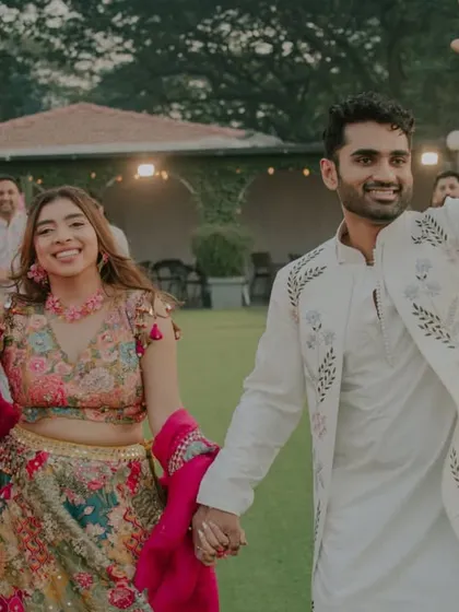 The bride and groom make their joyful entrance, waving to guests. The vibrant colors of their outfits and the happy faces of the crowd set the tone for a fun celebration.
