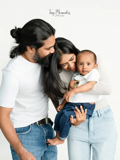A tender moment where the family comes together for a group hug. The baby's direct gaze at the camera, surrounded by his parents' love, makes this a captivating family photograph.