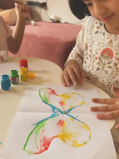 The moment of discovery. This little artist is amazed by the colorful butterfly print that appeared after pulling the paint-soaked rope.