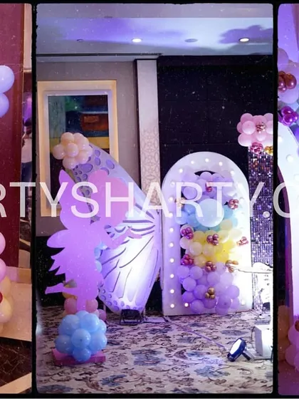 A collage showcasing various decor elements from a butterfly party, including a wishing board, a large butterfly wing photo prop, and a personalized welcome sign.