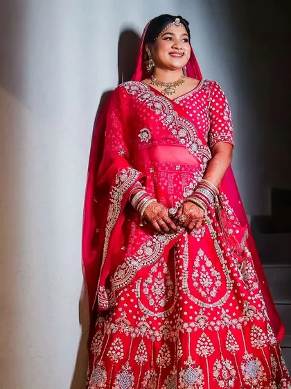 A full-length view of the bride in her stunning red lehenga. The makeup is balanced to look beautiful from a distance, ensuring she stands out.